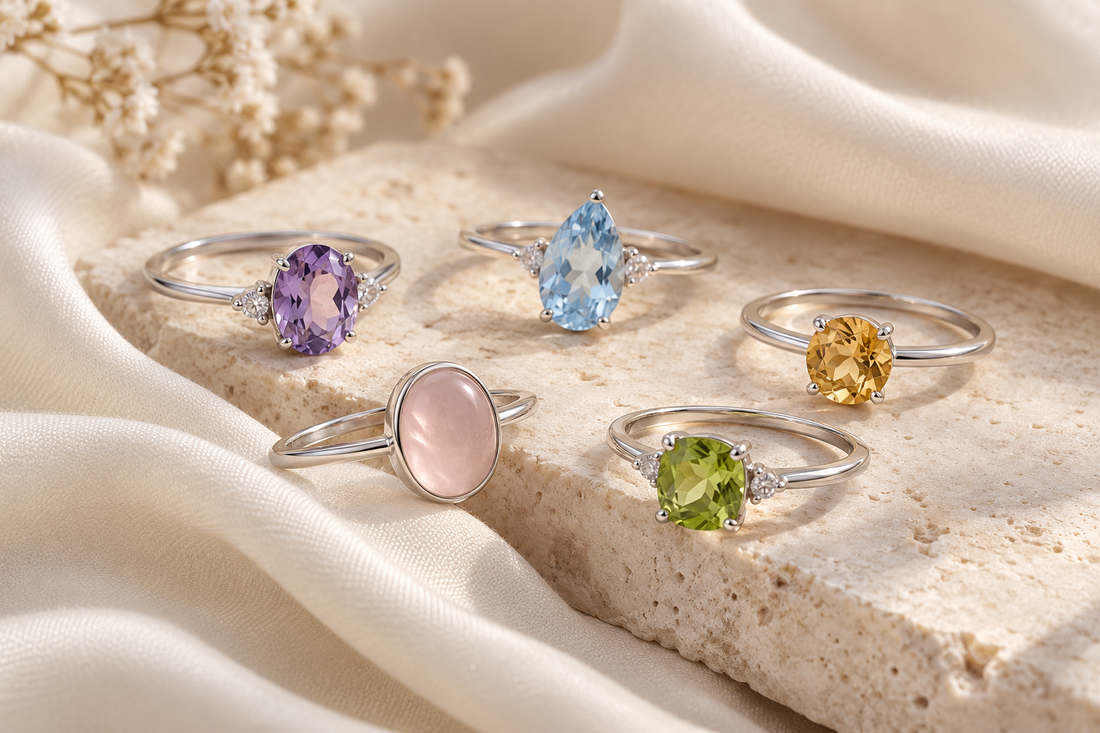 Illustration of five dainty sterling silver rings with colorful gemstones on an ivory background